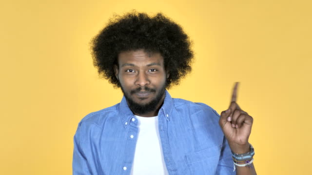 Hombre-afroamericano-agitando-el-dedo-a-rechazar-sobre-fondo-amarillo