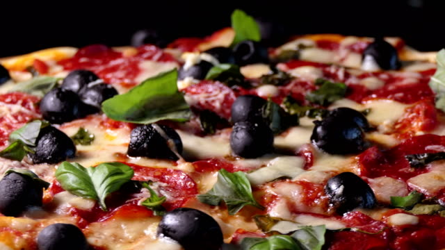 Pizza-mit-Salami-Peperoni,-schwarze-Oliven,-Basilikum-und-Mozarella-Käse-gebacken.-Schuss-zu-spinnen.