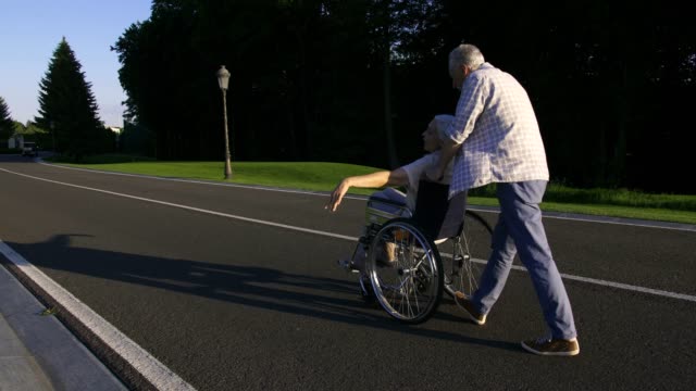 Senior-Mann-spinnende-Frau-im-Rollstuhl-in-den-park