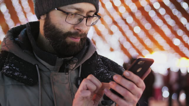 Hombre-barbudo-usar-aplicación-para-smartphone,-luces-de-Navidad.-Primer-plano-tiro