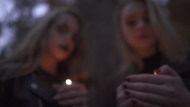 Zwei-blonde-Mädchen-mit-furchterregenden-Halloween-Make-up-hält-kleine-Kerzen-in-den-Händen-und-Blick-in-die-Kamera