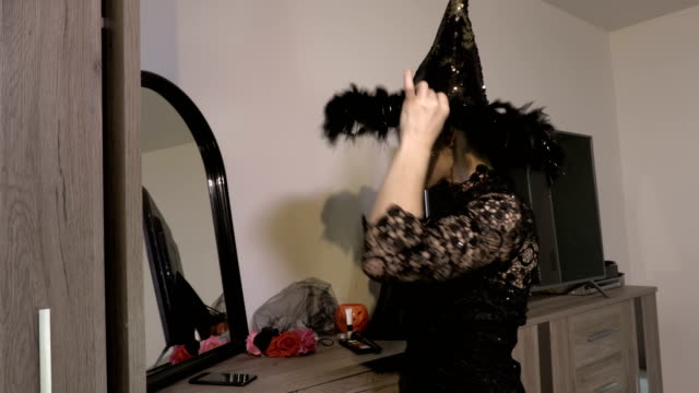Woman-with-Halloween-witch-hat-near-mirror