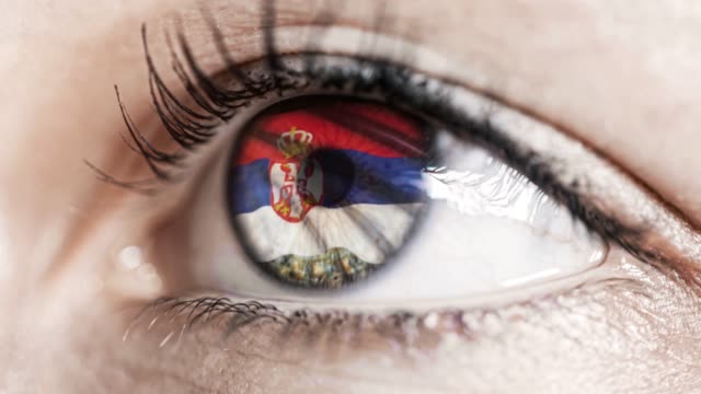 mujer-ojo-verde-en-primer-plano-con-la-bandera-de-Serbia-en-el-iris-con-el-movimiento-del-viento.-concepto-de-vídeo