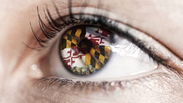 Mujer-ojo-verde-en-primer-plano-con-la-bandera-del-estado-de-Maryland-en-iris,-estados-unidos-de-América-con-movimiento-de-viento.-concepto-de-vídeo