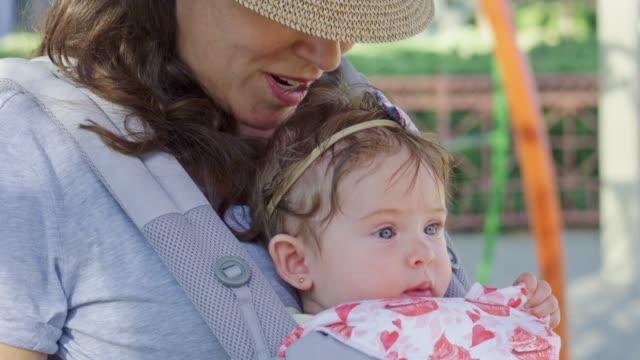 Woman-with-a-baby-in-carrier-kissing-baby's-head