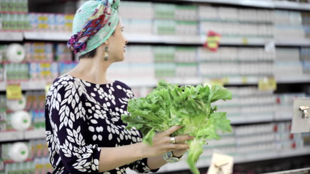 Two-female-friends-selecting-green-lettuce-in-grocery-store