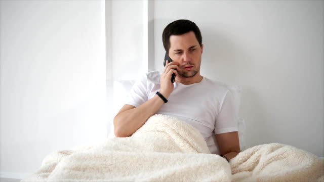 Mann-mit-einem-Handy-zu-sprechen,-wenn-im-Bett-liegend