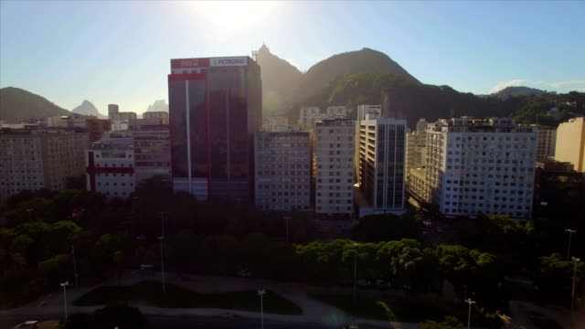 Rio-de-Janeiro-Aerial:-sideways-and-upwards-move-across-Botafogo-neighbourhood-revealing-Christ-the-Redeemer-behind-the-tall-buildings-at-sunset