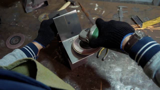 Craftsman-using-an-angle-grinder-for-polish-metal-detail-at-workshop.
