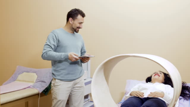 Arzt-spricht-mit-Patienten-während-der-Magnetfeldtherapie-in-Klinik