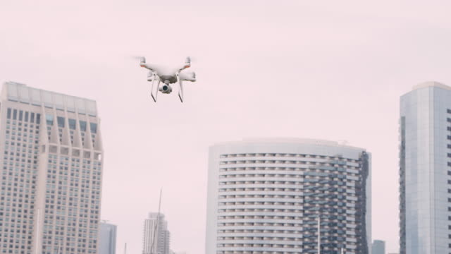 Quadrocopter-Drohne-mit-Kamera-auf-Gimbal-fliegen-in-den-Himmel-der-Stadt,-in-Zeitlupe-erschossen