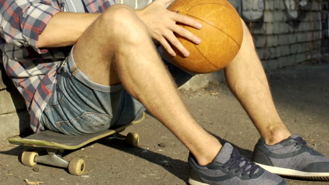 Teenage-boy-in-casual-clothing-sitting-on-skateboard,-active-leisure-time