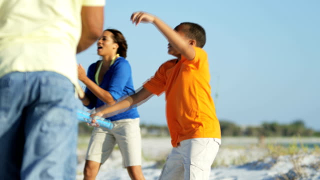 Ethnische-Eltern-und-Sohn-Baseball-zu-spielen,-am-Strand