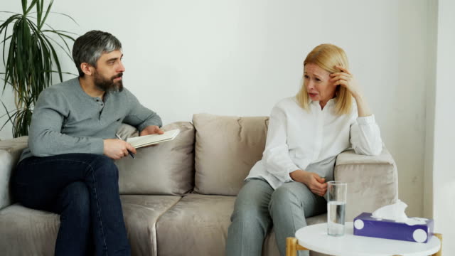 Male-experienced-psychologist-talking-and-calm-down-depressed-crying-woman-patient-during-psychotherapy-session