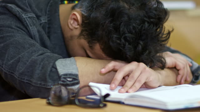 Erschöpfte-männliche-Schüler-schlafen-in-der-Vorlesung