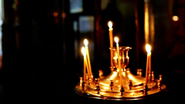Eine-Person-stellt-eine-Kerze-in-eine-Kerze-vor-religiöser-Symbole