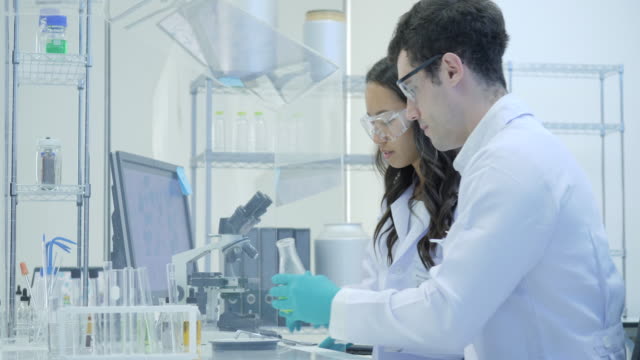 Dos-científicos-de-la-investigación-médica-trabaja-con-muestras-en-caja-de-aislamiento-en-el-laboratorio-moderno
