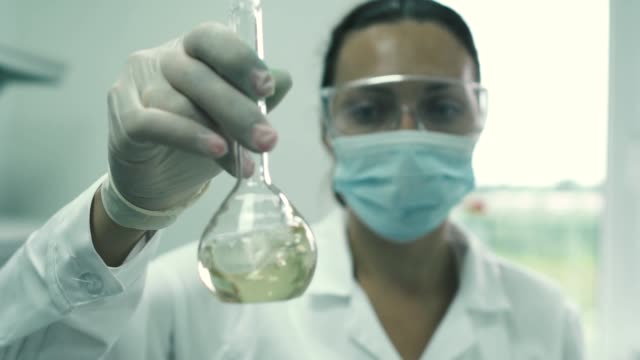 Girl-lab-assistant-stirs-the-liquid-in-a-flask