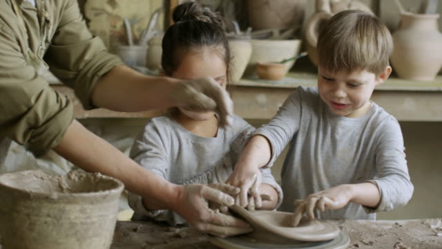 Ayudar-a-los-niños-hacer-cerámica-en-la-clase-artesanal