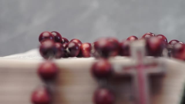 Bibel-und-Kreuz-Perlen-auf-einem-roten-Holztisch.-Schönen-Hintergrund.-Religion-Konzept-hautnah