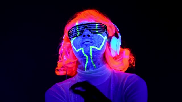 Langsame-Motin-Frau-mit-UV-Cyborg-Bemalung,-Perücke,-leuchtende-Gläser,-Kleidung,-Tanz-und-Musik-mit-Kopfhörern-hören.-Asiatische-Frau.-.