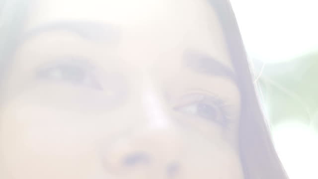 Close-up-of-kind-woman-face-in-haze,-low-angle-female-eyes-look-down-sun-rays