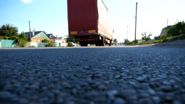 Red-truck-goes-at-the-asphalt-road.-Car-is-driving-at-the-highway-at-sunny-summer-day.-Traffic-close-up.-Low-angle-view-Slow-motion