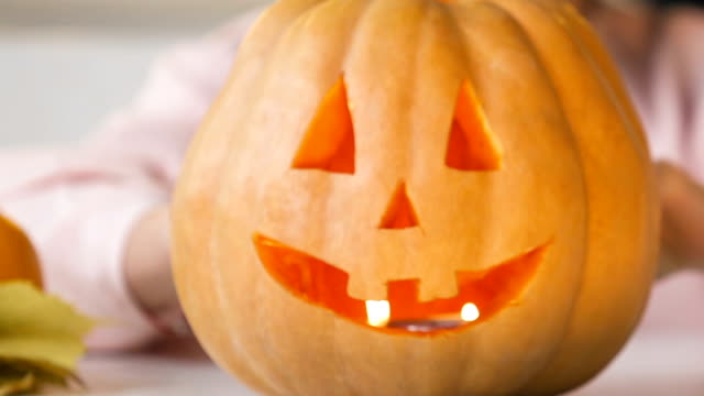 Girl-showing-carved-jack-pumpkin-with-burning-candle-inside,-preparing-for-party