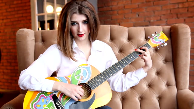 Frau-in-einem-weißen-Hemd-spielt-Gitarre-im-Hippie-Stil