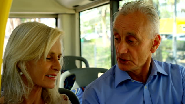 Senior-couple-interacting-with-each-other-while-travelling-in-bus-4k