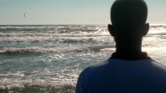 África-joven-solitaria-contemplando-el-mar.-Falta-África,-refugiados