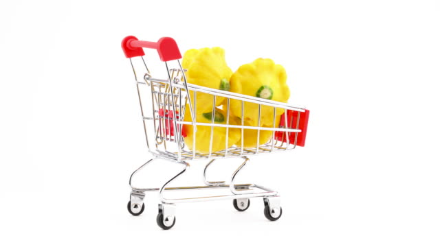 Supermarket-trolley.-Shopping-cart-with-yellow-pattypan-squashes.-Rotating.-Isolated-on-the-white-background.-Close-up.-Macro.