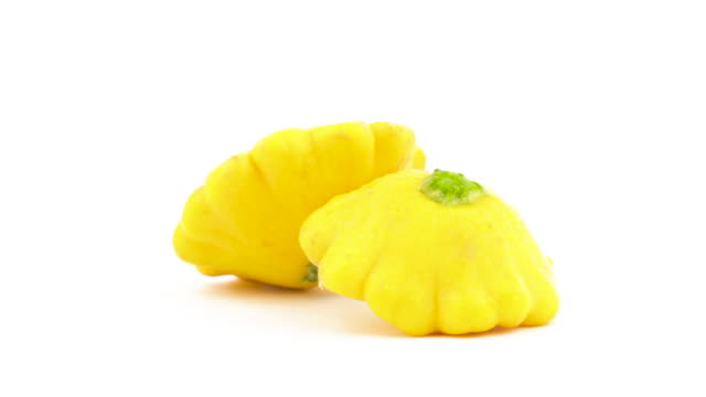 Two-yellow-patisson-squashes.-Rotating-on-the-turntable.-Isolated-on-the-white-background.-Close-up.-Macro.