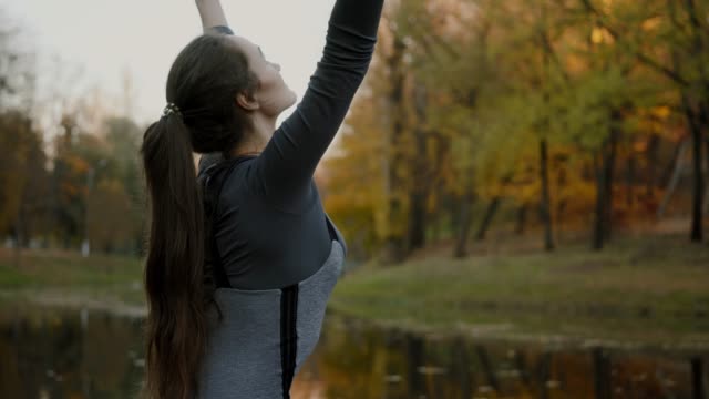 Young-woman-practicing-yoga-outdoors.-Female-meditate-outdoor-infront-of-beautiful-autumn-nature