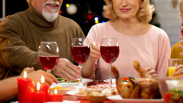 Family-raising-toast-at-Christmas-dinner,-tradition-to-get-together-for-holidays