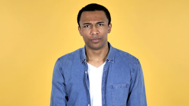Young-African-Man-Shaking-Head-to-Reject-Isolated-on-Yellow-Background