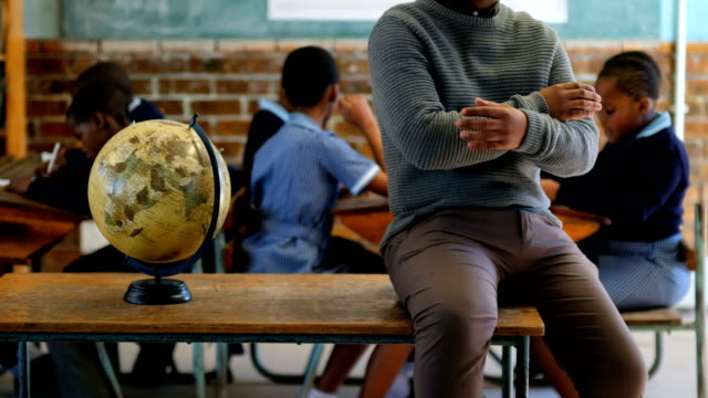 Male-teacher-relaxing-in-classroom-at-school-4k