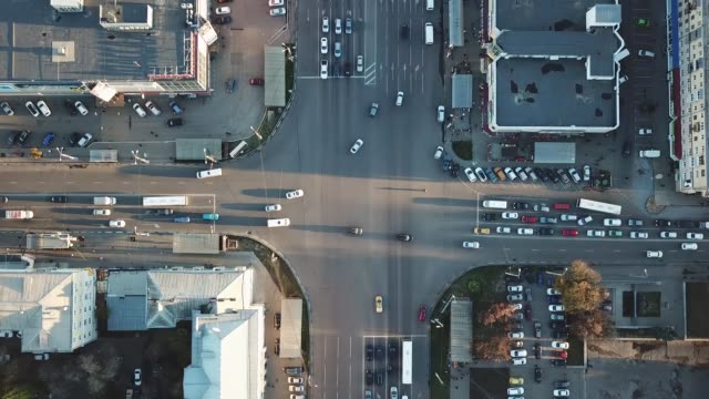 Top-view-of-road-intersection-and-parking-lot-taken-by-drone.-Moving-cars