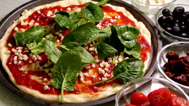 Preparando-pizza-cucurucho.-Colocación-de-espinacas-frescas-hojas-de-topping-de-la-pizza.