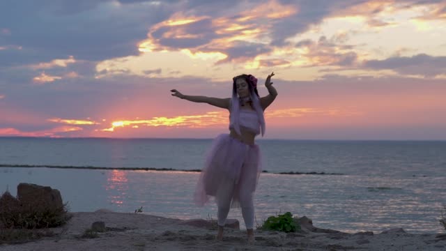 Cute-woman-with-bright-makeup-in-a-pink-dress-dancing-on-the-bank-of-the-river.-The-dance-of-a-sensual-girl-with-a-wonderful-hairstyle-with-flowers.-Slow-motion.