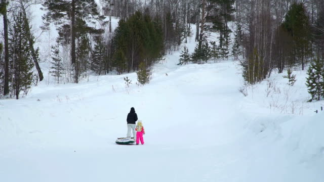 Mutter-und-Tochter-ein-Hügels-mit-Snow-Tube-Klettern