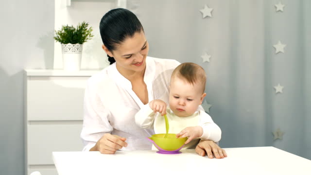 Madre-ayudando-a-bebé-con-comer-por-sí-misma