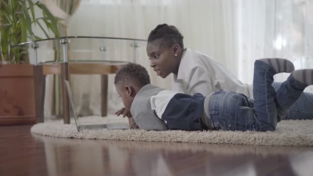 Afrikanische-Amerikanerin-mit-ihrem-niedlichen-Sohn-schaut-auf-den-Laptop.