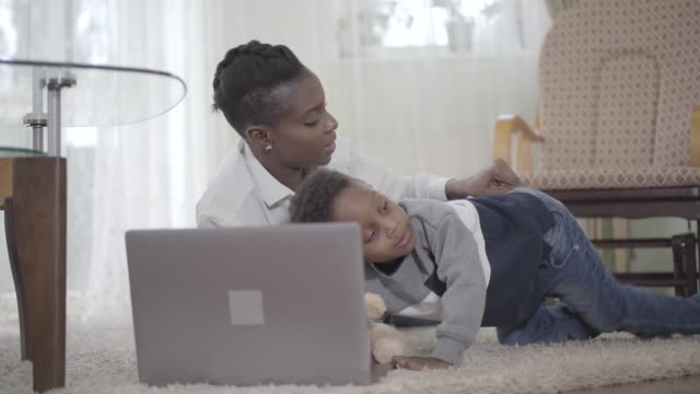 Mujer-afroamericana-con-su-lindo-hijo-mirando-la-Laptop.