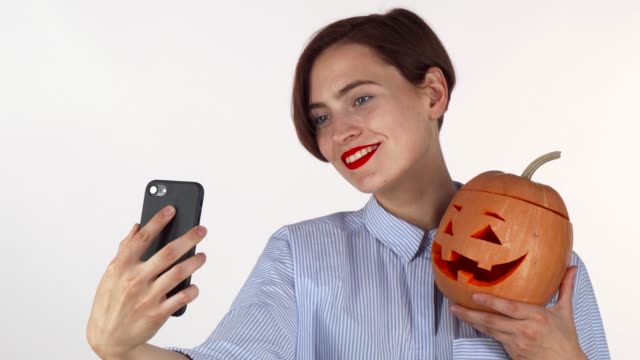 Schöne-junge-Frau-macht-Selfies-mit-Halloween-Kürbis