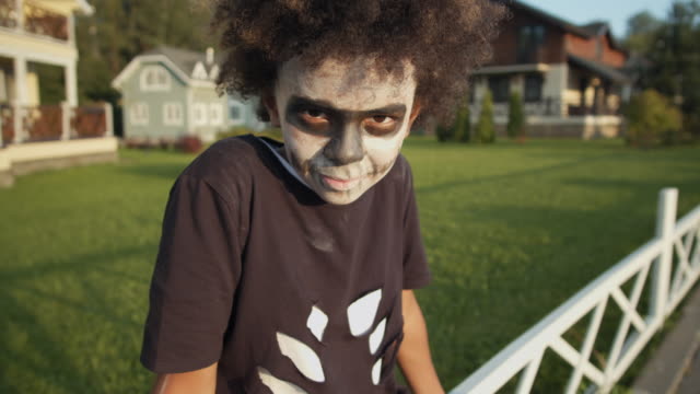 Portrait-of-Boy-Sitting-on-Fence-on-Halloween