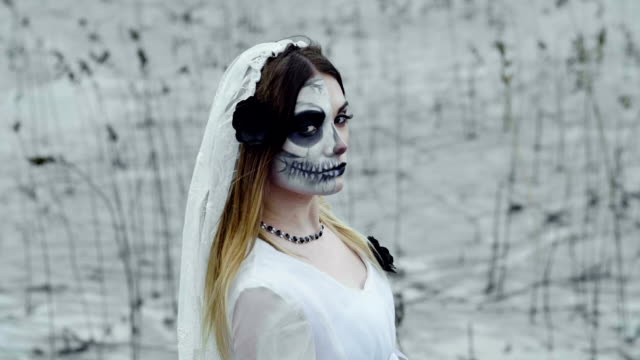 La-chica-con-maquillaje-de-miedo-para-Halloween-en-un-vestido-de-novia-blanco.-A-cámara-lenta.-Hd