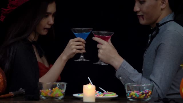 Couple-in-Halloween-costume-celebrating-with-glass-of-liquor-in-Halloween-night-party
