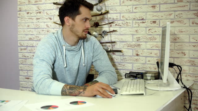 Young-bearded-businessman-in-grey-sweatshirt-working-in-bright-office.