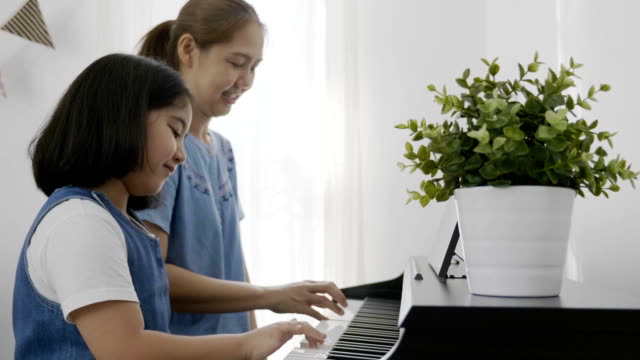 4K-:-Slow-motion-of-Asian-girl-playing-piano-with-her-mother,-Zoom-in-shot